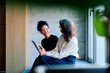 © we.bond.creations - Two diverse business women collaborating and discussing content on a digital tablet, fostering mentorship and connection in an office