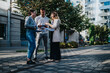 © qunica.com - Three professionals discuss documents outdoors on a city street. They review papers and talk together in a casual business setting.