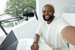 © Wavebreak Media - Adult African man reaching forward smiling taking selfie at home in beanie with mic, copy space