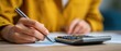 © Alexander LW - A young Asian woman uses a calculator to calculate her balance and prepare tax deductions. Close-up of her hand holding a pen.