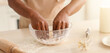 © Prostock-studio - Hands are working the dough in a clear bowl on a kitchen counter. A rolling pin and whisk sit nearby. The setting looks like a home kitchen ready for baking.