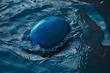 © nsit0108 - Close up of a blue ball floating on dark blue water with gentle ripples and small bubbles