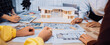 © InfiniteFlow - A group of architects and designers engage in a collaborative design session, surrounded by architectural plans and a detailed model. The bright office fosters creativity. SACTR