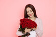 © New Africa - Happy woman with bouquet of red roses on pink background