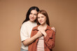 © New Africa - Portrait of mother and her teenage daughter holding hands on beige background