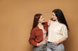 © New Africa - Mother and her smiling teenage daughter posing on beige background. Space for text