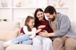© New Africa - Pregnant woman, her husband and daughter on sofa at home