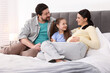 © New Africa - Pregnant woman, her husband and daughter on bed at home