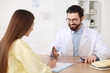 © New Africa - Woman having appointment with doctor at wooden desk in clinic