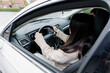 © Nataliya - A young girl with a passenger sits in a car holding the steering wheel.