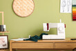 © Pixel-Shot - Tailor's workplace with sewing machine near green wall in atelier
