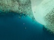 © AmazingAerialAgency - Aerial view of turquoise waters meet the sandy shore, kayaks dotting the deep blue, a tranquil contrast of colors and textures at Menjangan Kecil Island, Karimunjawa, Indonesia.