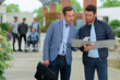 © auremar - two businessmen standing with folders outdoors
