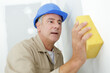 © auremar - male builder cleaning wall with sponge
