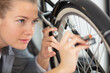 © auremar - cute caucasian female worker holding and repairing bicycle wheel