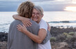 © luciano - Romantic senior couple of women embrace each other on the seashore at sunset light, two embraced people stay together expressing love and tenderness