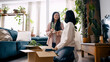 © DMegias - Two young women unpacking moving boxes, arranging houseplants, and chatting in their new, plant filled home