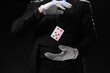 © Pixel-Shot - Male magician with levitating playing card on dark background