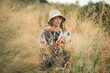 © chokniti - Woman traveler wearing colorful patterned sweater and hat standing in golden grass field under warm sunlight enjoying nature, outdoor adventure, and peaceful autumn atmosphere at countryside