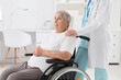 © Pixel-Shot - Senior woman in wheelchair with doctor holding her shoulder at hospital. Care concept