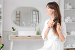 © Pixel-Shot - Beautiful young happy woman brushing her hair in bathroom at home