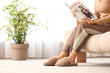© Pixel-Shot - Young woman in soft comfortable slippers reading magazine at home