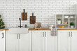 © Pixel-Shot - Utensils and shelving unit on kitchen counter near white brick wall