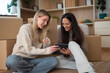 © Dexon Dee - Happy women checking digital tablet during apartment relocation