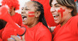 © DisobeyArt - Latin red sport fans screaming while supporting their team - Football supporters having fun at competition event - Soft focus on senior african woman face