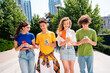 © deagreez - Young friends casually walking with smartphones outdoors in a modern city environment on a sunny day