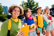 © deagreez - Group of cheerful young students walking outdoors with book on a sunny day, enjoying friendly companionship and education