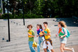 © deagreez - Group of cheerful friends enjoying a day outdoors carrying book and backpacks, representing friendship