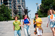 © deagreez - Group of happy young friends walking together outdoors in a sunny urban setting, enjoying companionship and youthful energy