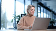 © Katsiaryna - A woman is sitting at a desk with a laptop in front of her