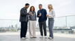 © illustratica - Diverse group of colleagues sharing a smartphone on a rooftop terrace overlooking city