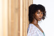 © Wavebreak Media - African American woman leaning against studio wood slats, in white knit, green camisole, copy space