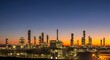 © Zenith - Industrial refinery complex at dusk with illuminated towers and storage tanks against vibrant sunset sky
