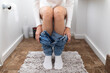 © kieferpix - Woman sitting on toilet in bathroom with jeans down concept of restroom hygiene