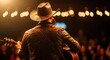 © Desingora - Back view of a country music singer wearing a cowboy hat and leather jacket playing an acoustic guitar on stage with warm lighting