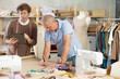© JackF - Adult male tailor showing elderly male assistant pattern drawing on tablet in sewing workshop
