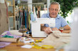 © JackF - Elderly man works in a sewing workshop. Process of making a clothing collection. Tailor sews a dress to order