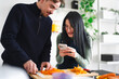 © Studio Marmellata - A man slices carrots while a woman looks at her phone in a kitchen. They are preparing food together.