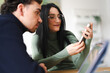© Studio Marmellata - A man and a woman are looking at a smartphone together. The woman is wearing glasses and holding the phone.