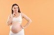 © New Africa - Choosing name for baby. Thoughtful pregnant woman on orange background, space for text