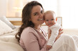 © New Africa - Portrait of smiling mother with her cute baby near sofa at home