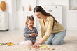 © New Africa - Mother and her daughter playing with toys on floor at home