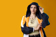 © New Africa - Beautiful young woman with piercings in windbreaker on yellow background. Space for text