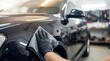 © Stitch - Car detailing professional hands wiping a black vehicle with a microfiber cloth