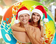 © New Africa - Happy couple with Santa hats and inflatable ring against blurred background