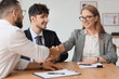 © Pixel-Shot - Male business mediator shaking hands with clients at table in office